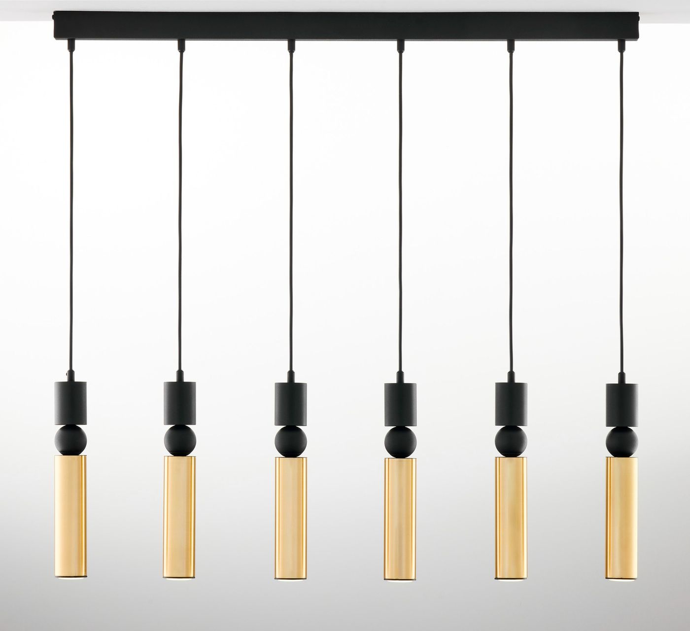 Lampa wisząca Alas z sześcioma źródłami światła GU10, z czarnymi elementami oraz złotymi kloszami w formie cylindrów. Produkt zawieszony na prostokątnej, czarnej podstawie, z widocznymi przewodami. Tło jasne, jednolite.