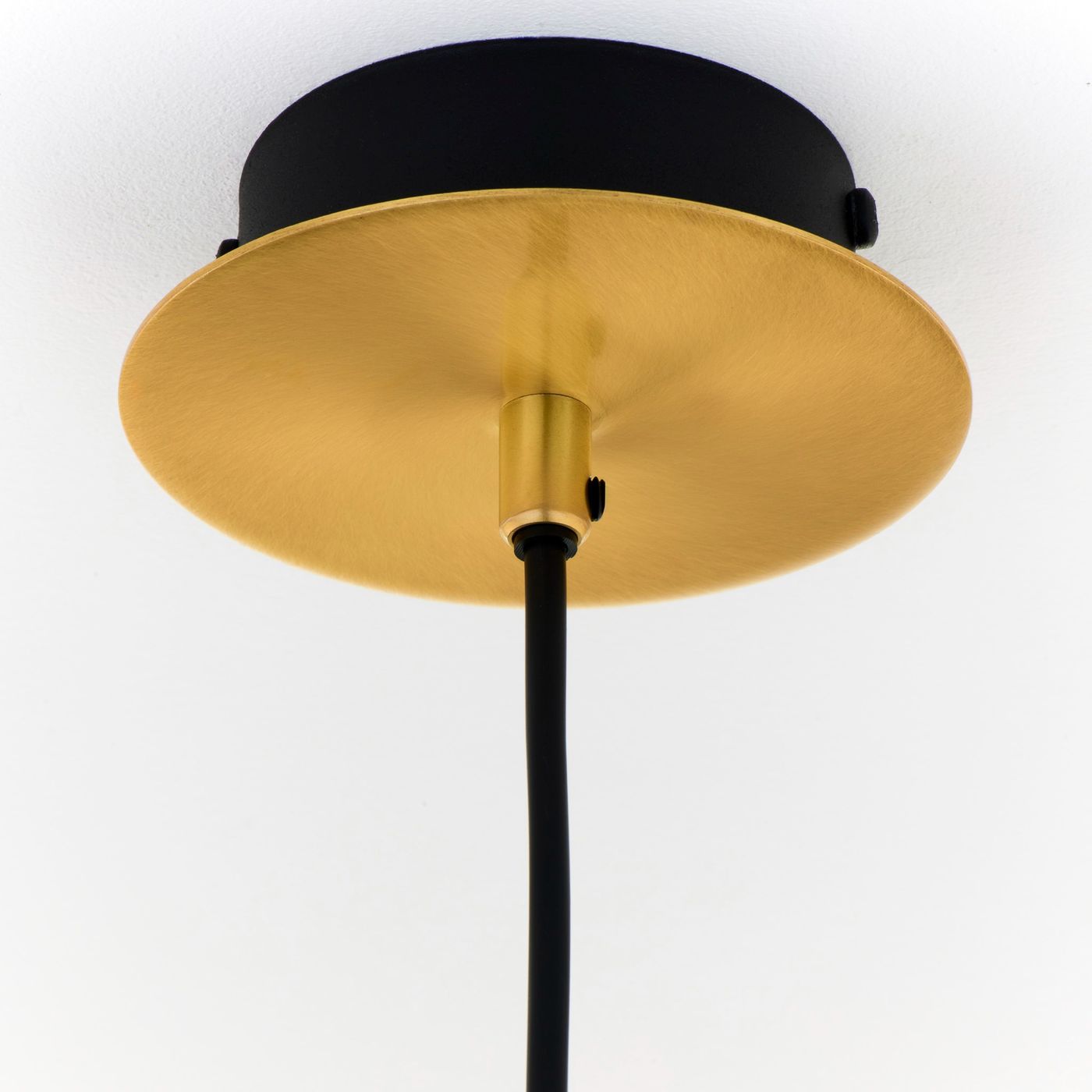 Lampa wisząca Alas z jedną oprawą GU10, złota, z metalowym, okrągłym, błyszczącym kloszem oraz czarnym kablem. Widok od dołu, ukazujący połączenie z sufitem.