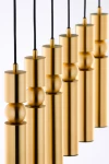 Lampa wisząca Alas w kolorze złotym, składająca się z sześciu cylindrycznych opraw, zawieszonych na czarnych przewodach. Elementy mają różne wysokości i kształty, w tym kuliste detale. Tło białe, co podkreśla elegancki design.