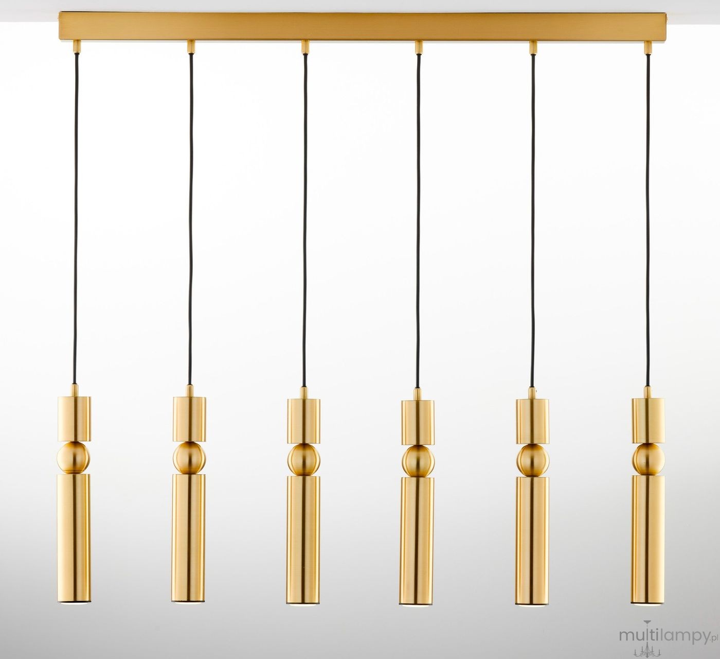 Lampa wisząca Alas z sześcioma oprawami GU10 w kolorze złotym. Elementy w formie cylindrów zawieszone na czarnych przewodach. Lampa zamontowana na prostokątnej podstawie. Jasne tło podkreśla elegancki design.