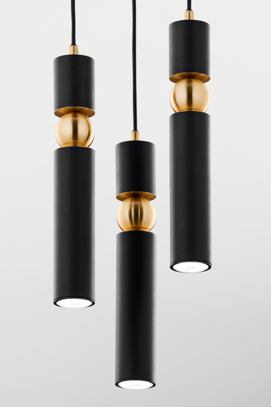 Lampa wisząca Alas z trzema źródłami światła GU10, w kolorze czarnym. Składa się z cylindrycznych elementów z matowego metalu oraz złotych kulistych detali. Zawieszona na czarnym przewodzie, prezentuje nowoczesny design.