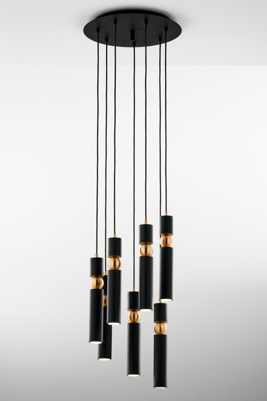 Lampa wisząca Alas z siedmioma oprawami GU10, w kolorze czarnym, z dekoracyjnymi elementami w odcieniu mosiądzu. Produkt wiszący, z długimi przewodami, zawieszony na okrągłej podstawie sufitowej, prezentujący nowoczesny design.