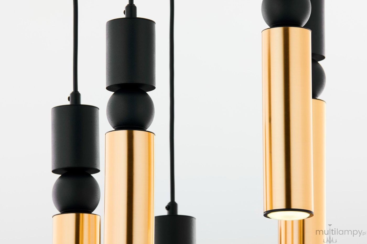 Lampa wisząca Alas z pięcioma źródłami światła GU10, w kolorze czarnym i złotym. Wysokie cylindryczne elementy z błyszczącego metalu i matowe wykończenie, zawieszone na czarnym przewodzie, tworzą nowoczesny design.