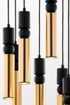 Lampa wisząca Alas z siedmioma źródłami światła GU10, w kolorze czarnym i złotym. Ujęcie z bliska, pokazujące cylindryczne, błyszczące elementy w złotym kolorze oraz matowe, czarne akcenty. Wisi na czarnych przewodach na jasnym tle.