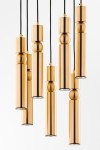 Lampa wisząca Alas z 7 źródłami światła GU10, w kolorze złotym. Składa się z cylindrycznych elementów o różnych wysokościach, zawieszonych na czarnych kablach. Produkt ma nowoczesny design, idealny do zastosowania w eleganckich wnętrzach.