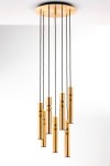 Lampa wisząca Alas w kolorze złotym z siedmioma oprawami na żarówki GU10. Zawieszona na czarnych kablach, z cylindrycznymi i kulistymi elementami. Kąt ujęcia frontalny, ukazujący elegancki design i nowoczesny styl.
