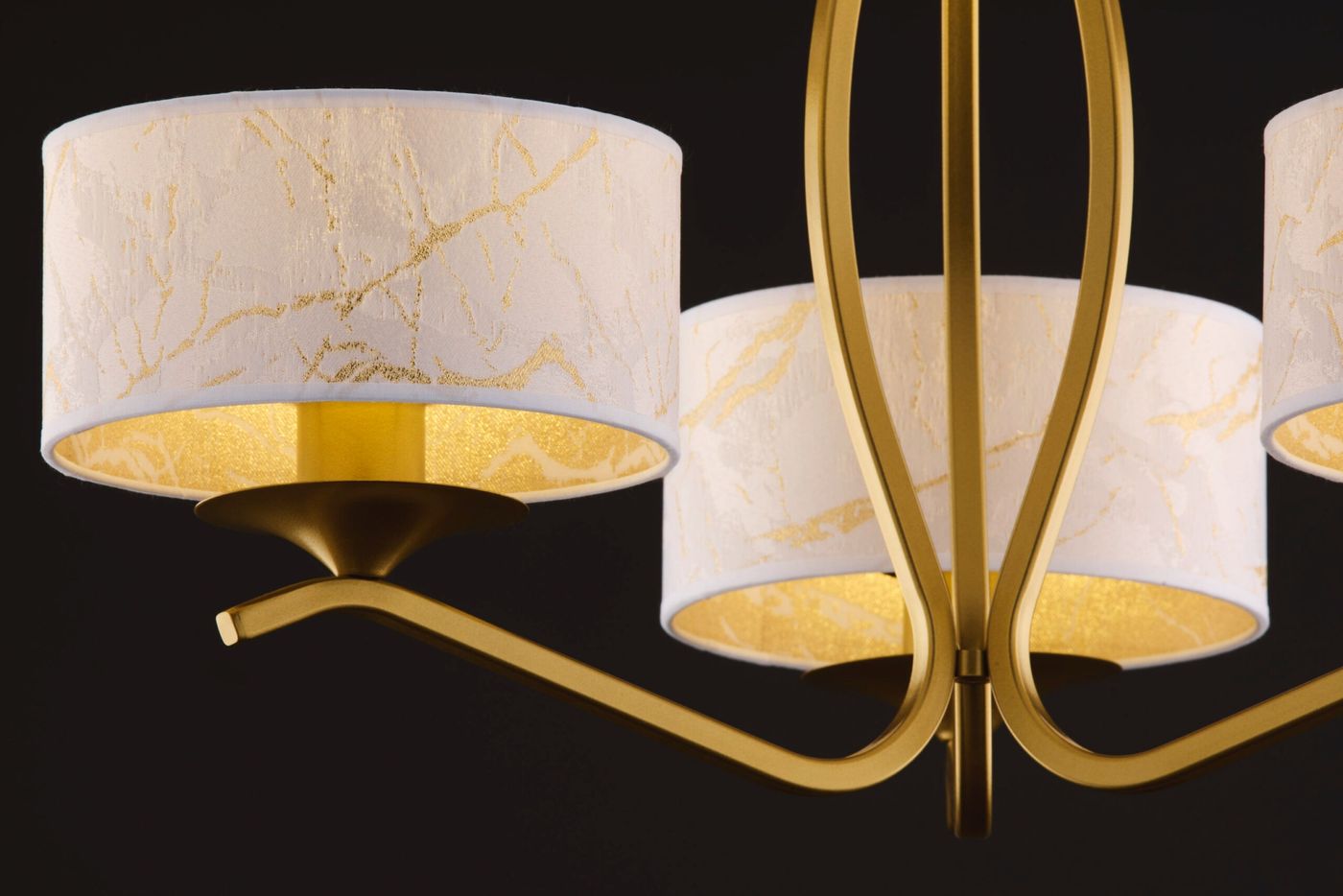 Kaszmir żyrandol w kolorze złotym z trzema kloszami E27. Klosze białe z delikatnym złotym wzorem, montowane na metalowych ramionach. Widok zbliżony na detale kloszy i mocowania.