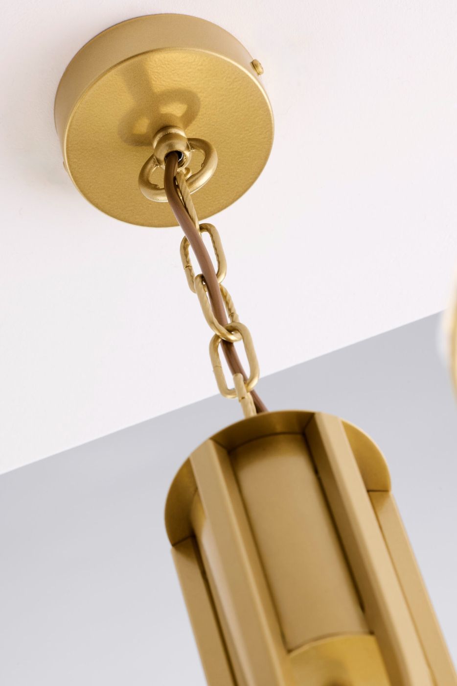 Złoty żyrandol Arthur z trzema miejscami na żarówki E27, zawieszony na metalowej łańcuchowej linki. Widoczny jest także okrągły sufitowy uchwyt. Całość ma nowoczesny, geometryczny kształt i jest w kolorze złotym, co nadaje elegancki wygląd.