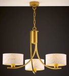 Żyrandol Arthur 3xE27 w kolorze złotym z białymi kloszami. Klosze mają delikatny wzór, a całość zawieszona na złotej łańcuchowej konstrukcji. Ujęcie z dołu, prezentujące szczegóły designu oraz wykończenia.