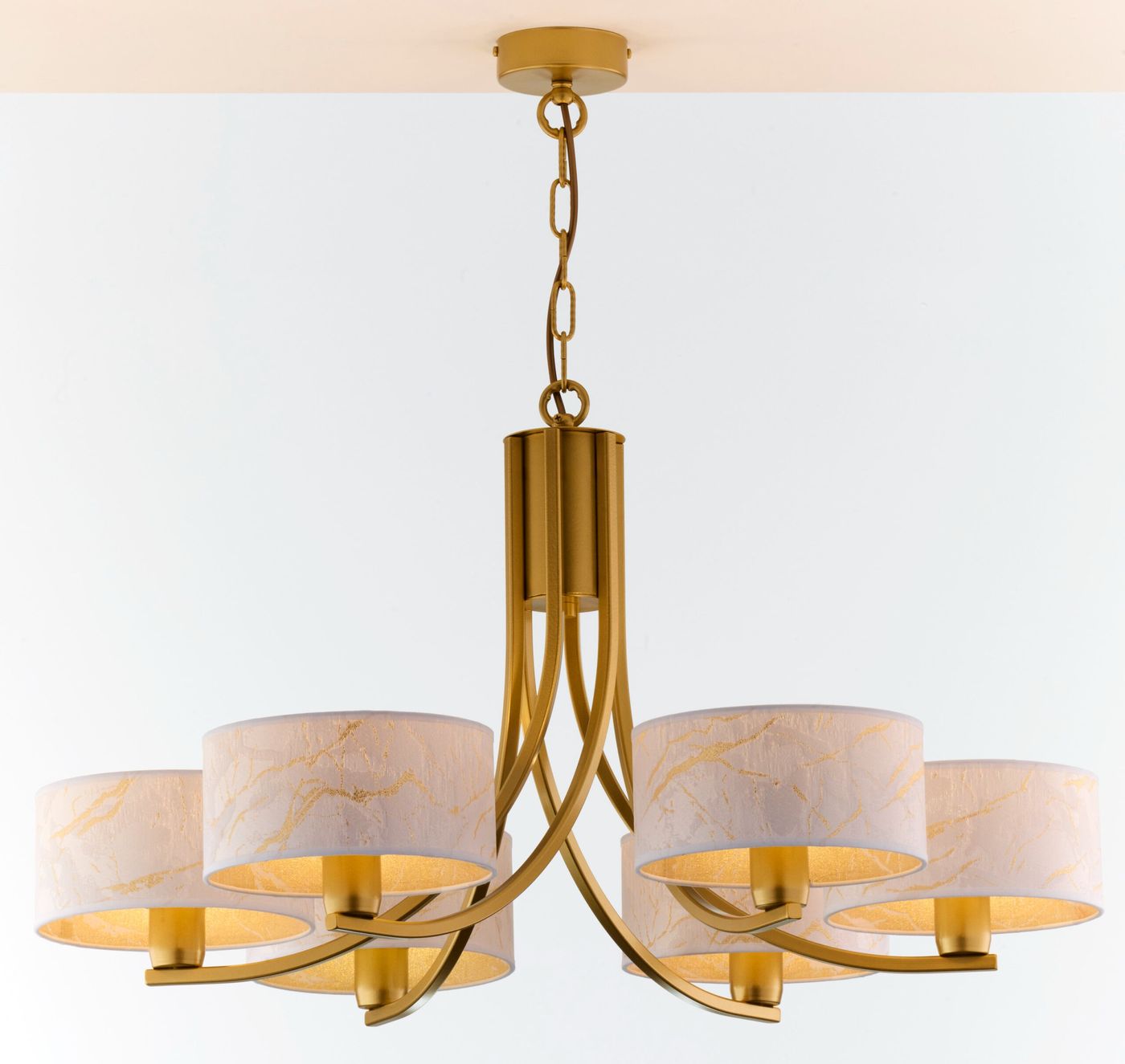 Żyrandol Arthur 6xE27 w kolorze złotym z białymi kloszami, zawieszony na łańcuchu. Klosze mają delikatny wzór z złotymi akcentami. Produkt ma elegancki, nowoczesny design, idealny do aranżacji wnętrz.