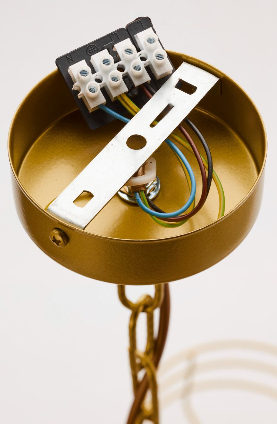 Zbliżenie na złoty element montażowy żyrandola Arthur 3xE27, z widocznymi przewodami elektrycznymi w kolorach brązowym, niebieskim, zielonym i żółtym. Ujęcie pokazuje wewnętrzną konstrukcję oraz uchwyty do podłączenia. Tło jasne i proste.