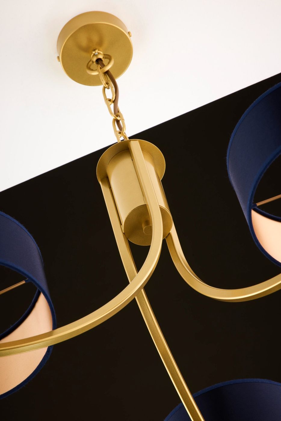 Złoty żyrandol Arthur z trzema kloszami w granatowym kolorze, zawieszony na złotym łańcuchu. Widoczna metalowa konstrukcja z zaokrąglonymi ramionami oraz eleganckie detale w formie cylindrycznego mocowania. Tło czarne, podkreślające kolorystykę lampy.