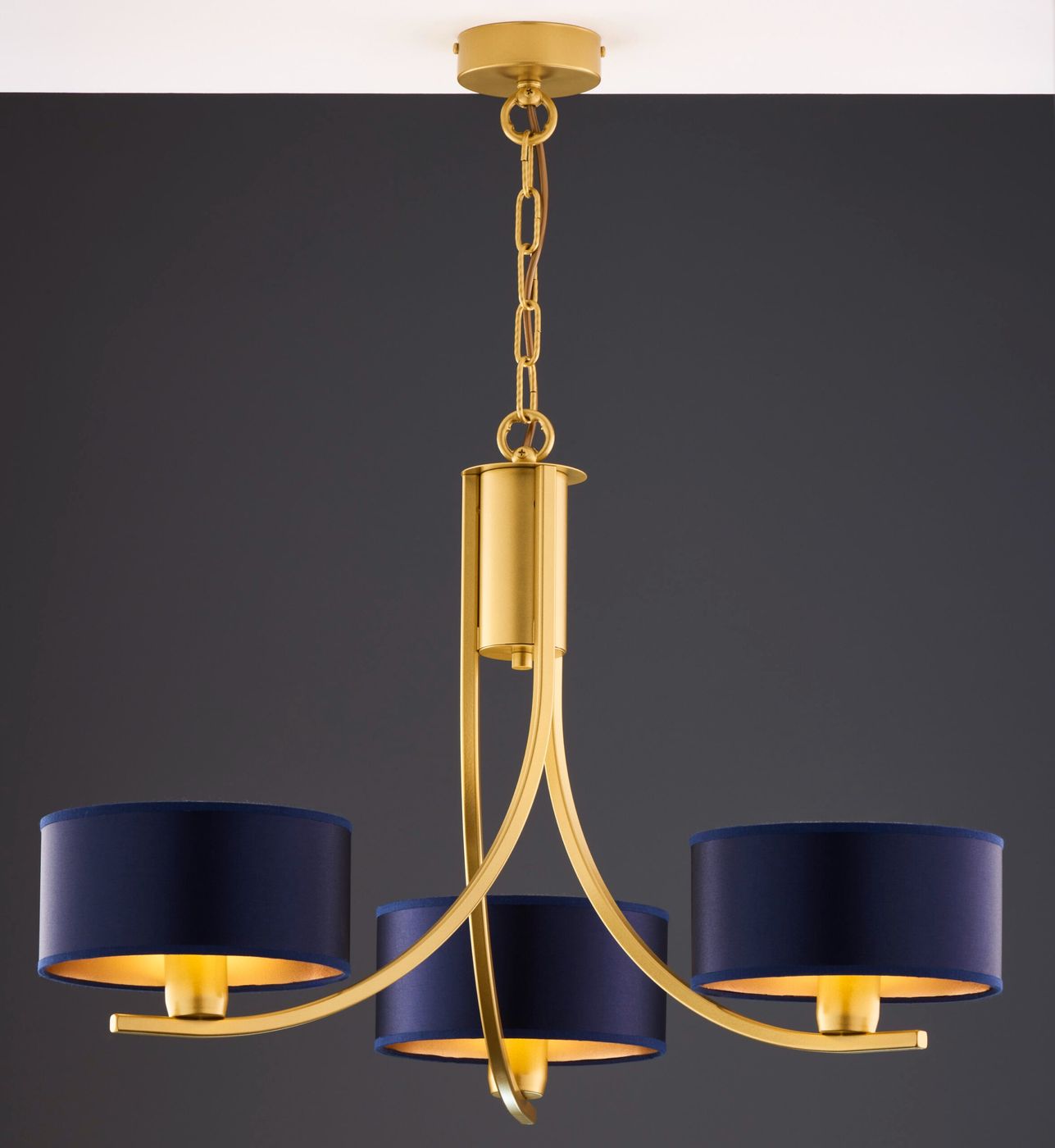 Żyrandol Arthur z trzema oprawami E27, w kolorze złotym z granatowymi abażurami. Ułożony w pionie, zawieszony na łańcuchu. Elegancki design z zaokrąglonymi kształtami i matowym wykończeniem, idealny do nowoczesnych wnętrz.