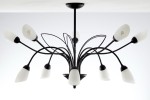 Żyrandol Gloriosa w kolorze czarnym i białym, z dziesięcioma oprawami G9. Posiada smukłe, gięte ramiona z czarnym wykończeniem oraz matowe białe klosze w kształcie łez. Ujęcie z góry, ukazujące elegancką konstrukcję i detale.