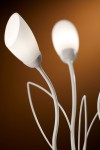 Lampa stołowa Gloriosa 3xG9 w piaskowo-szarej kolorystyce. Posiada trzy klosze w kształcie tulipanów, wykonane z białego matowego szkła, osadzone na cienkich, giętych metalowych ramionach. Ujęcie z bliska, na tle w odcieniu brązowym.