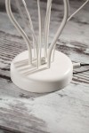 Lampa stołowa Gloriosa w kolorze piaskowo-szarym z białą podstawą. Widoczna okrągła baza z przewodami w stylu minimalistycznym. Ujęcie z boku, ukazujące detale konstrukcji i mocowania.