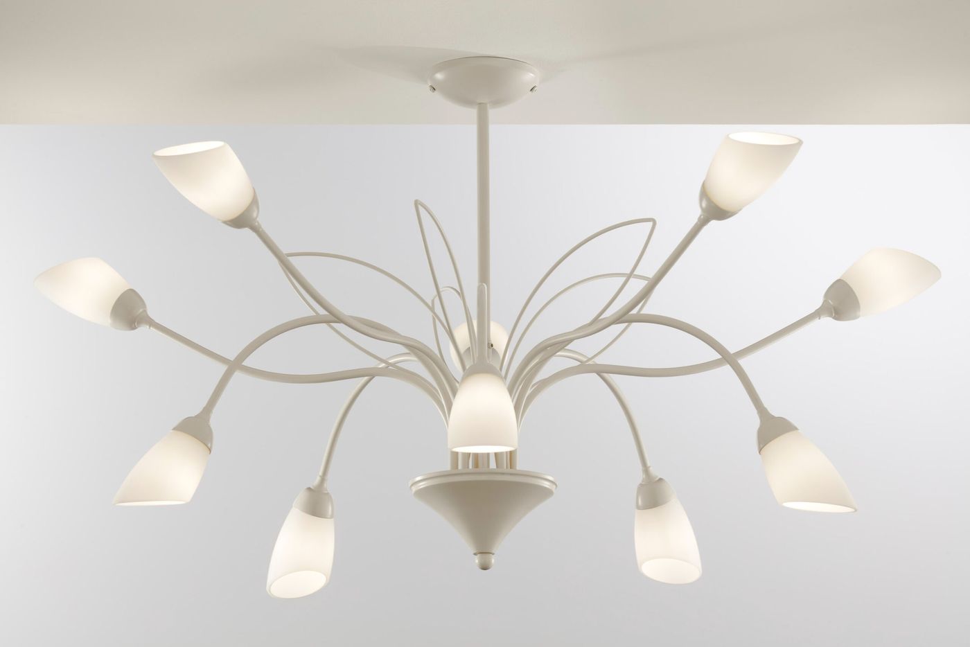 Żyrandol Gloriosa w kolorze piaskowo-szarym, z dziesięcioma kloszami G9, o łukowatych ramionach. Ujęcie z dołu, pokazujące symetryczny układ kloszy w kształcie stożków, zamocowanych na długich, cienkich ramionach.