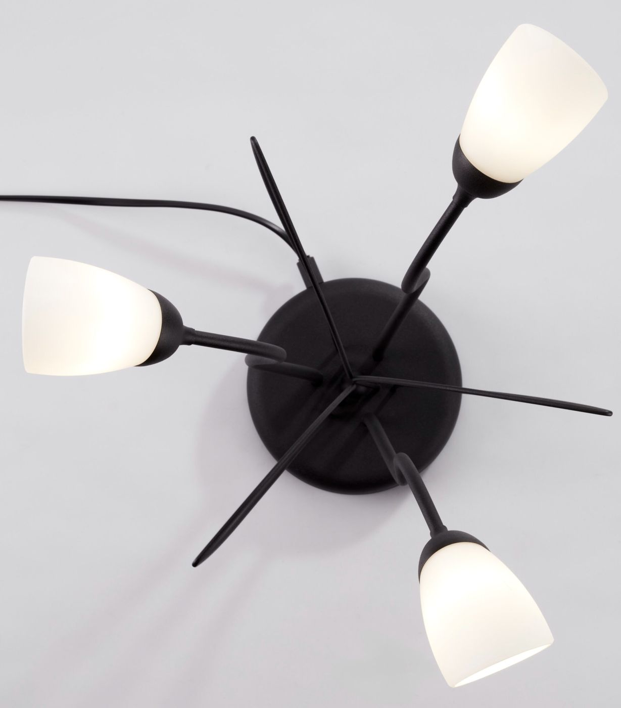 Lampa stołowa Gloriosa w kolorze czarnym z trzema kloszami z białego szkła. Klosze mają kształt lekko stożkowaty i są umiejscowione na długich, cienkich ramionach. Ujęcie z góry, ukazujące układ lampy.