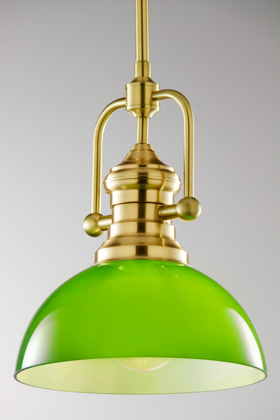 Lampa wisząca Platino 1xE27 w kolorze szczotkowanego mosiądzu z zielonym kloszem. Produkt zawieszone na długim przewodzie, z metalowymi detalami i okrągłym, gładkim kloszem, który emituje światło. Tło proste, jednolite.