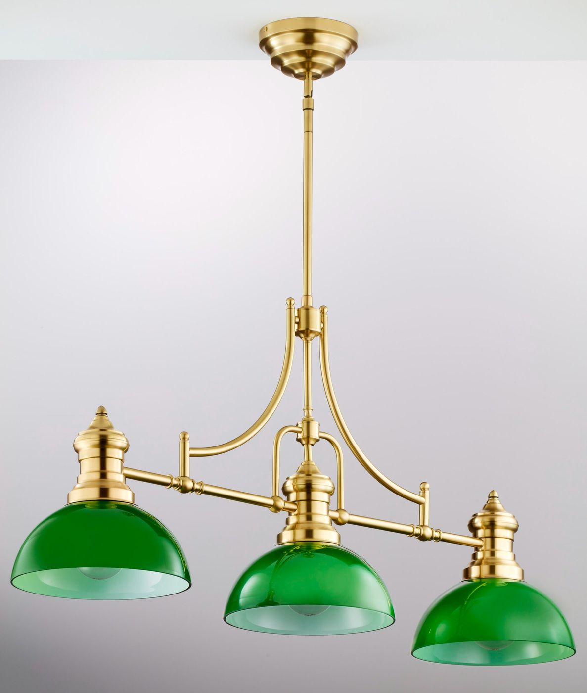 Lampa wisząca Platino 3xE27 w kolorze szczotkowanego mosiądzu z trzema zielonymi kloszami. Ujęcie frontalne, wisząca konstrukcja z eleganckimi detalami. Klosze o półokrągłym kształcie, metalowe mocowanie, do aranżacji wnętrz.