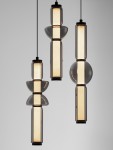 Lampa wisząca Glorica z trzema źródłami LED, czarna. Składa się z trzech elementów o różnych kształtach: cylindrów i kul, z przezroczystymi kloszami. Zawieszona na cienkich linkach, emituje ciepłe światło, na jednolitym tle.