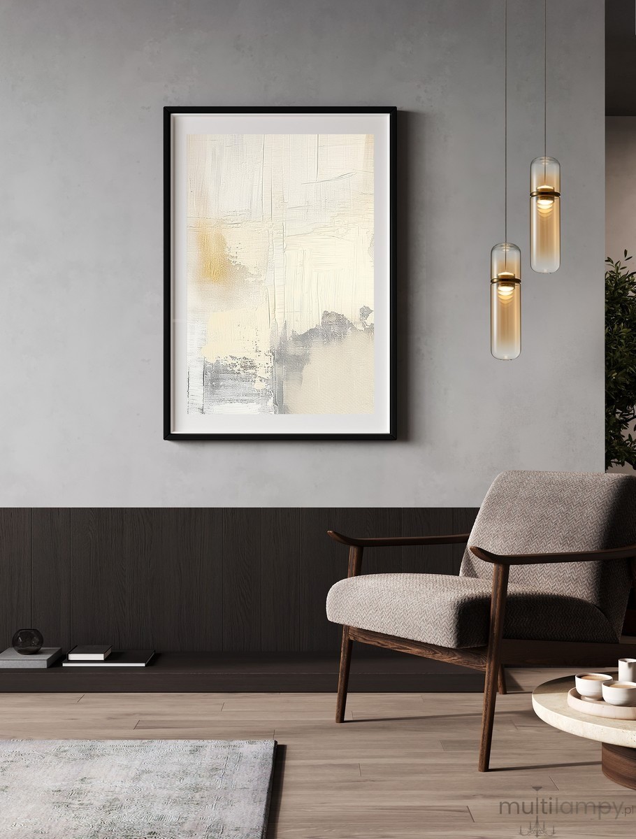 Lampa wisząca Rebalvo 1xLED 7W w kolorze złotym, o prostym cylindrycznym kształcie, zawieszona na cienkim przewodzie. Widoczna w nowoczesnym wnętrzu z szaro-beżowymi tonami, obok abstrakcyjnego obrazu i stylowego fotela.