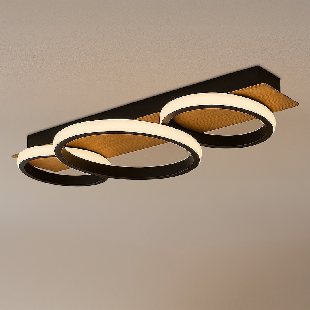Czarna lampa sufitowa LED Rowena o mocy 18W, z trzema okrągłymi pierścieniami w kolorze białym i drewnianą listwą. Ujęcie z boku ukazuje nowoczesny design i połączenie materiałów. Oświetlenie o temperaturze barwowej 4000K.