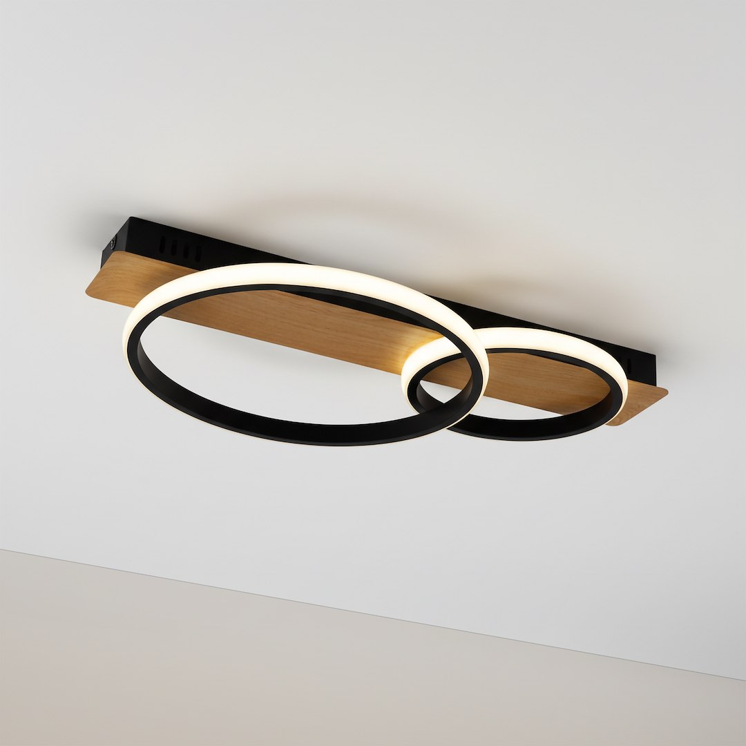 Lampa sufitowa LED Rowena, 14W, 4000K, z czarnymi okręgami i drewnianym elementem, zamontowana na suficie. Okręgi mają delikatne białe światło, co podkreśla nowoczesny design. Ujęcie z dołu, na jednolitym tle.