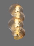 Lampa wisząca Tanvera z jedną żarówką LED 15W. Składa się z trzech bursztynowych, teksturowanych kloszy o eleganckim kształcie, zawieszonych na cienkim kablu. U dołu złoty element mocujący. Tło szare, co podkreśla design lampy.