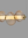 Lampa wisząca Tanvera z jedną żarówką LED 30W, złota z bursztynowymi, żłobionymi kloszami. Ujęcie z przodu, pokazujące trzy okrągłe klosze na metalowej podstawie, zawieszone na cienkim przewodzie. Tło szare, minimalistyczne.