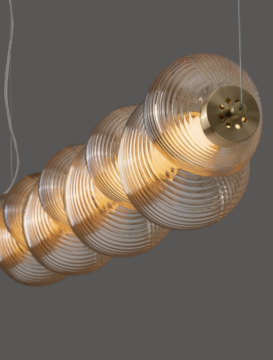 Lampa wisząca Tanvera z jednym źródłem LED 30W, w złotej oprawie. Szklany klosz o spiralnej fakturze, bursztynowy kolor, zawieszona na cienkim przewodzie. Widok z góry, eksponujący detale klosza i oprawy.