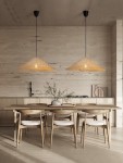 Lampa wisząca Torenla z czarnego rattanu, z kloszem w kształcie stożka, zawieszona na cienkim kabelku. W tle nowoczesna kuchnia z drewnianymi meblami i stołem. Wnętrze o stonowanej kolorystyce, z naturalnym oświetleniem.