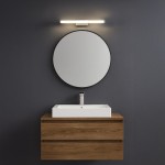 Kinkiet Mirore L30 LED 5W 4000K IP44 w kolorze srebrnym, zamontowany nad okrągłym lustrem. Oświetlenie umieszczone na ciemnoszarym tle, nad umywalką na drewnianej szafce. Prosty, nowoczesny design.