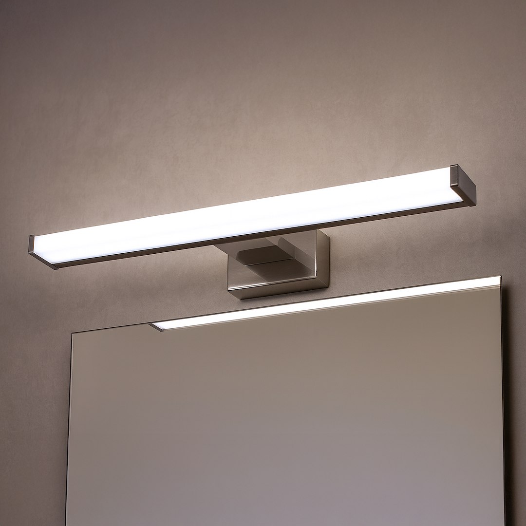Mirore kinkiet L40 LED 8W 4000K IP44 w kolorze srebrnym, zamontowany na ścianie, z prostokątnym korpusem i białym kloszem. Oświetlenie skierowane w dół, idealne do łazienki, widoczny fragment lustra poniżej.