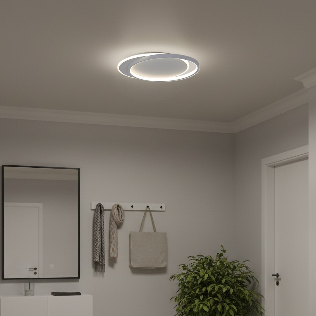 Lampa sufitowa LED Cordoba 30W 4000K w kolorze białym, okrągła, zamontowana na suficie w nowoczesnym wnętrzu. Emituje jasne światło, otoczona dwoma cienkimi pierścieniami. Tło w stonowanej szarości, z dodatkami takimi jak lustro i roślina.