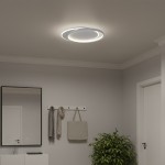 Lampa sufitowa LED Cordoba 30W 4000K w kolorze białym, okrągła, zamontowana na suficie w nowoczesnym wnętrzu. Emituje jasne światło, otoczona dwoma cienkimi pierścieniami. Tło w stonowanej szarości, z dodatkami takimi jak lustro i roślina.