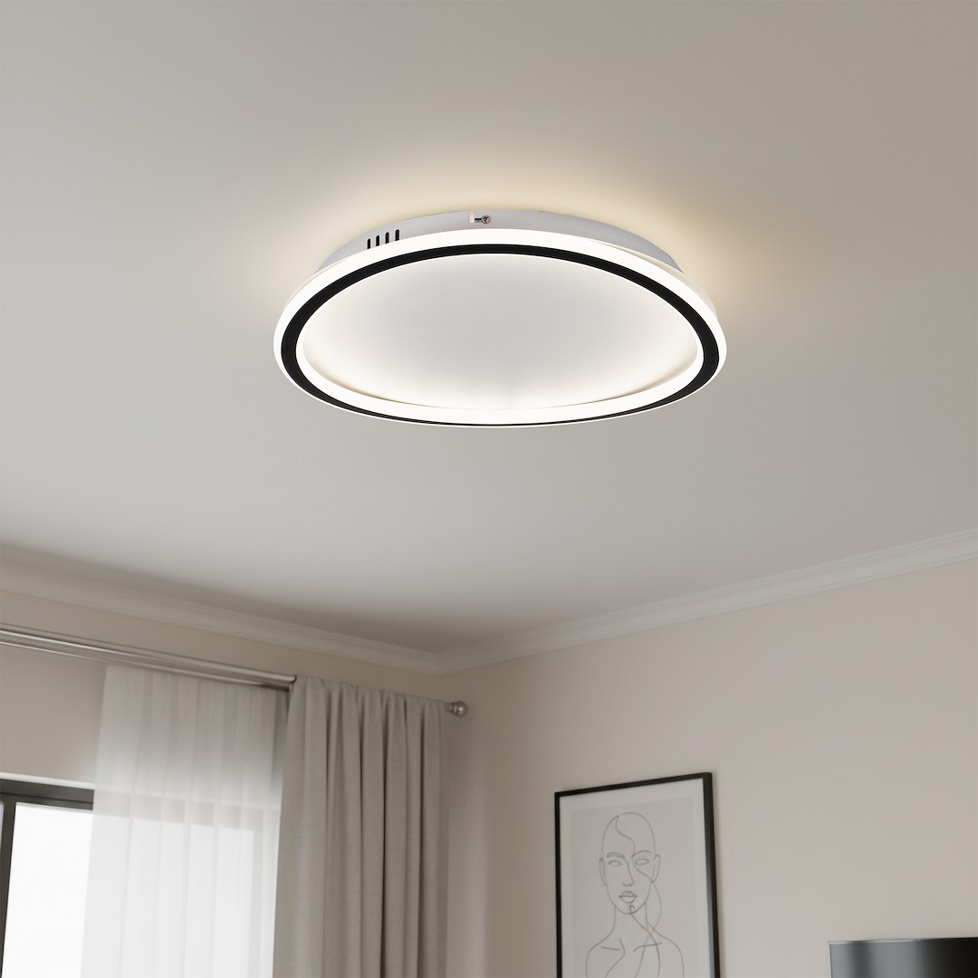 Cali Round lampa sufitowa LED 30W 4000K w kolorze czarnym i białym. Okrągła forma, zamontowana na suficie, z białym kloszem i czarną obwódką. Światło rozpraszane w dół, w tle zasłony i obraz na ścianie.