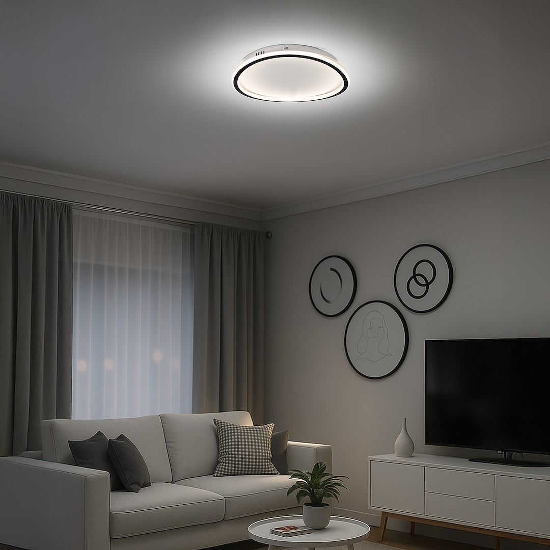 Cali Round lampa sufitowa LED 30W 4000K w kolorze czarnym/białym, zamontowana na suficie. Okrągły kształt z subtelnym podświetleniem, w nowoczesnym wnętrzu z sofą, telewizorem i dekoracjami na ścianie.