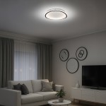 Cali Round lampa sufitowa LED 30W 4000K w kolorze czarnym/białym, zamontowana na suficie. Okrągły kształt z subtelnym podświetleniem, w nowoczesnym wnętrzu z sofą, telewizorem i dekoracjami na ścianie.
