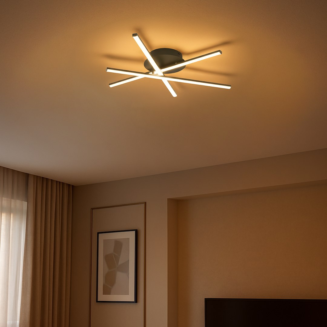 Czarna lampa sufitowa LED o mocy 12W i temperaturze barwowej 4000K, złożona z sześciu prostokątnych elementów w układzie promienistym, zamontowana na suficie w nowoczesnym wnętrzu. Tło w stonowanej kolorystyce.