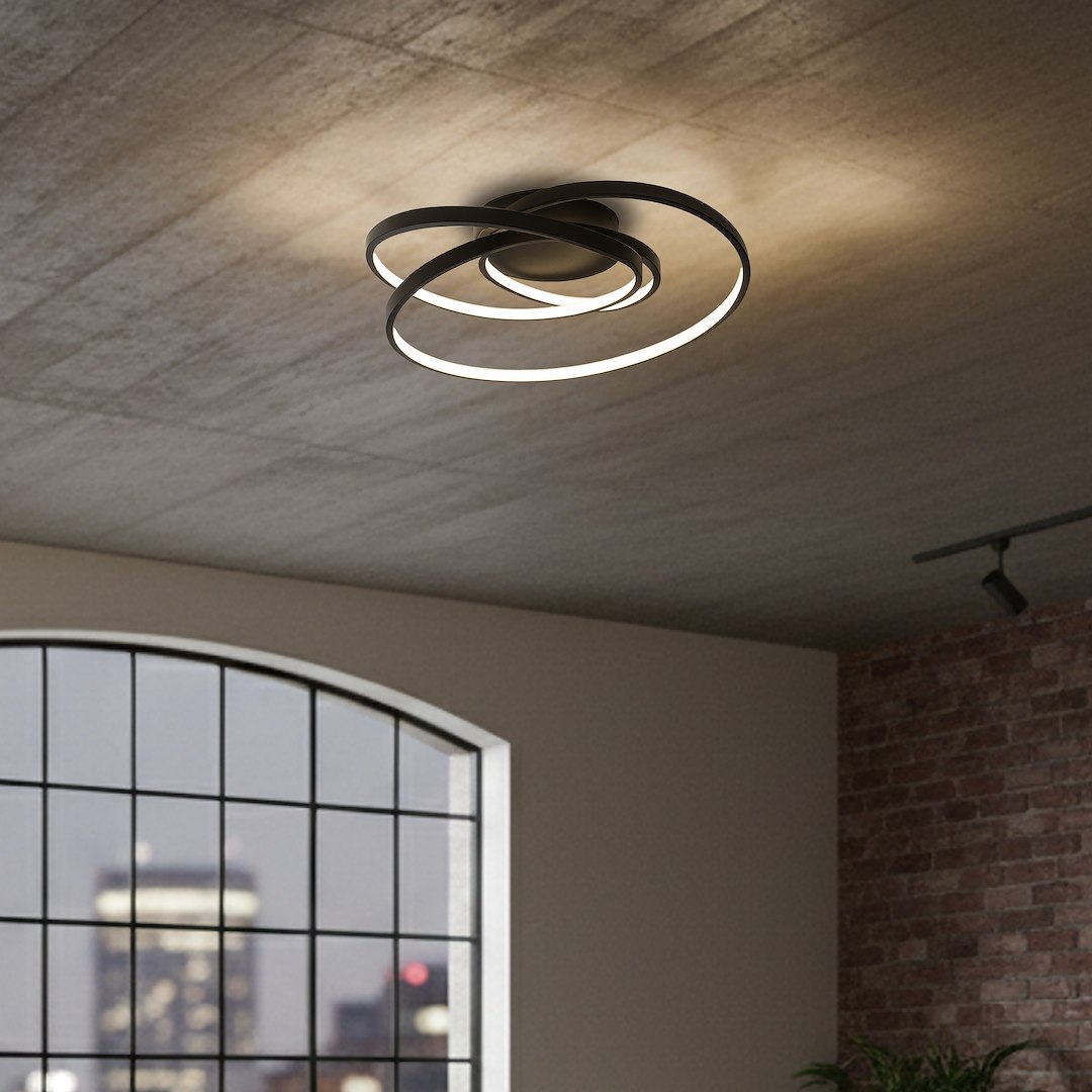 Czarna lampa sufitowa LED Turner o mocy 32W, 4000K, z charakterystycznym designem składającym się z dwóch okręgów, zawieszona na tle surowego sufitu. Oświetlenie tworzy nowoczesny efekt świetlny w pomieszczeniu.