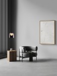 Czarna lampa wisząca Tavenco z żarówką LED 5W, umieszczona w nowoczesnym wnętrzu. Lampa wisi nad szarym fotelem z miękkim obiciem, obok drewniana ława. Tło w jasnych odcieniach z dekoracyjnym obrazem na ścianie.