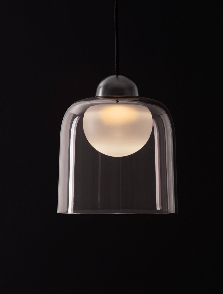 Lampa wisząca Tavenco z pojedynczym źródłem LED 5W, w czarnej obudowie. Klosz z przezroczystego szkła o cylindrycznym kształcie, z białą kulą wewnątrz, zawieszona na czarnym przewodzie. Ujęcie frontalne.