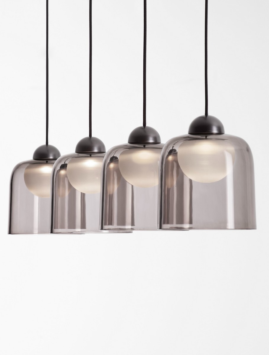 Czarna lampa wisząca Tavenco z czterema kloszami LED 20W. Klosze o lekko przyciemnionym odcieniu szarości, okrągłe, z białymi żarówkami, zawieszone na czarnych przewodach. Ujęcie frontalne, produkt wisi w powietrzu na jednolitym tle.