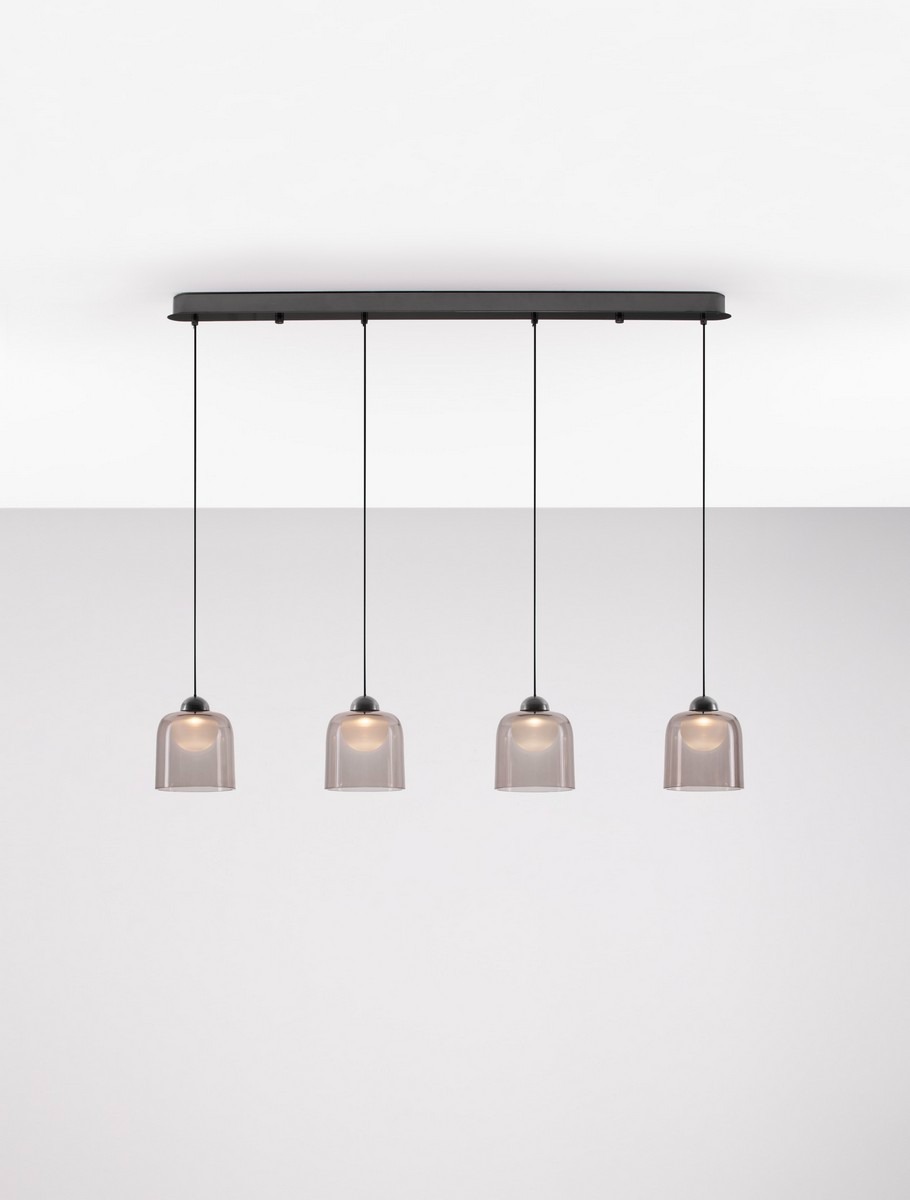 Lampa wisząca Tavenco z czterema kloszami LED 20W w kolorze czarnym. Klosze mają przezroczyste, lekko przyciemnione szkło. Produkt montowany pod sufitem, zawieszony na cienkich linkach, w prostym, nowoczesnym stylu. Tło jasne, jednolite.