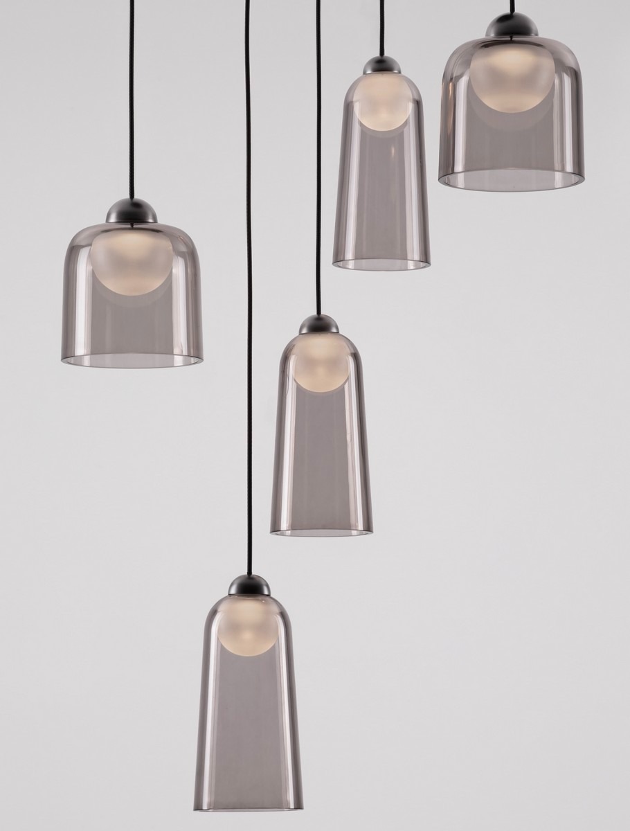 Lampa wisząca Tavenco z pięcioma kloszami LED 24W, czarna, z przezroczystymi, szklanymi kloszami. Klosze mają okrągłe, matowe źródło światła, zawieszone na czarnych przewodach. Produkt wisi w grupie, tworząc nowoczesną aranżację. Tło białe.