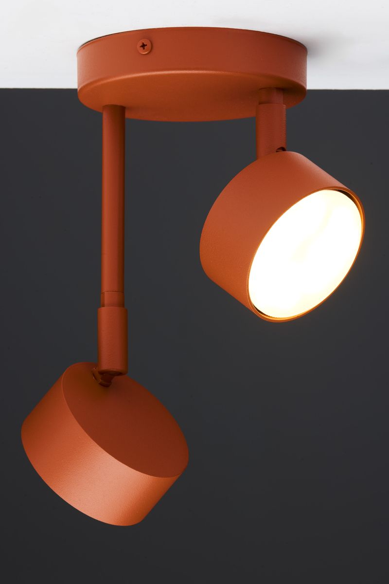 Lampa wisząca Nemo w ceglanej kolorystyce z dwoma reflektorami na regulowanych ramionach. Metalowa konstrukcja z matowym wykończeniem, montowana do sufitu. Reflektory skierowane w dół, idealne do oświetlenia przestrzeni.