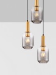 Lampa wisząca Querisa 3xE27 w kolorze złotym z przezroczystymi kloszami. Wisi na czarnych przewodach, prezentując trzy źródła światła. Klosze mają prosty, cylindryczny kształt, a metalowe elementy są wykończone w złotej barwie.