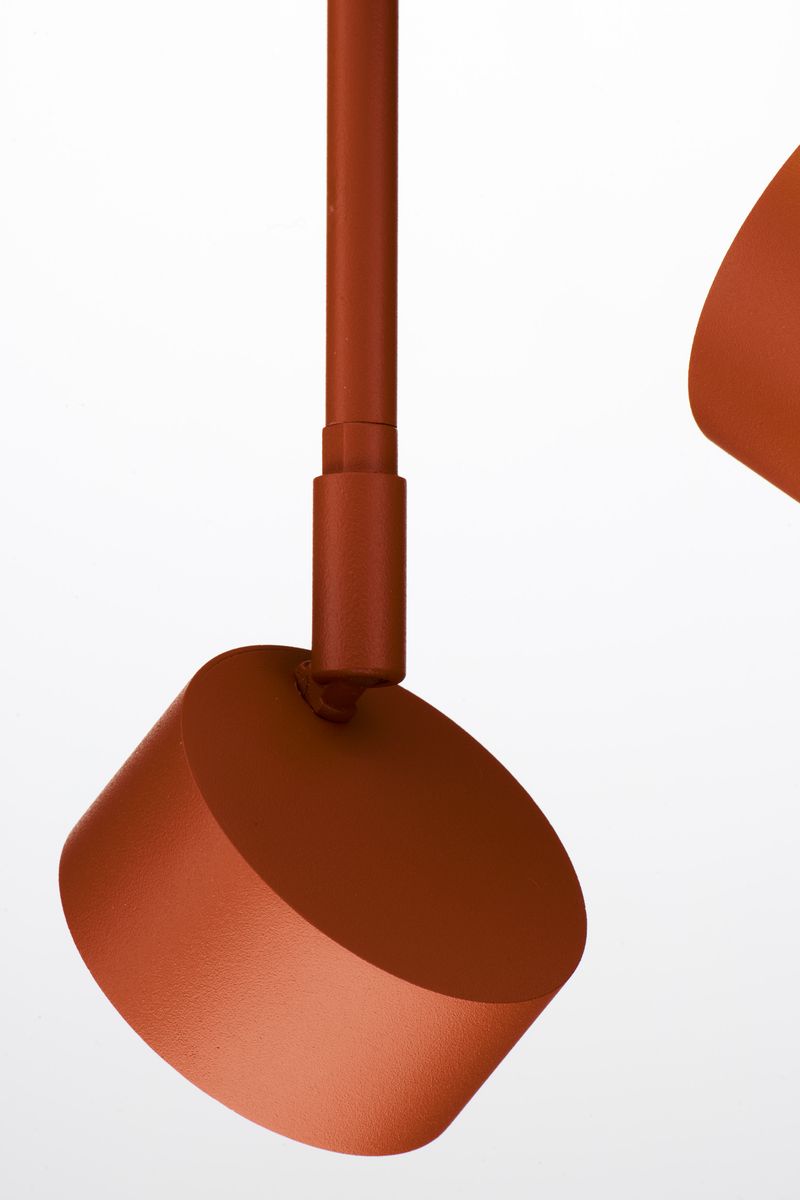 Lampa wisząca Nemo w kolorze ceglastym z trzema oprawami GX53. Ujęcie z boku, ukazujące okrągłe, matowe klosze. Elementy metalowe o gładkiej fakturze, zamontowane na cienkim stelażu. Tło białe, co podkreśla intensywność koloru.
