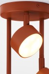 Lampa wisząca Nemo w kolorze ceglastym z trzema punktami świetlnymi na okrągłej podstawie. Ujęcie z bliska, ukazujące jeden z kloszy, wykonany z matowego metalu, emitujący ciepłe światło. Elementy montażowe w kolorze dopasowanym do kloszy.